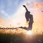 woman being freed from chains. arms in the air cheering.