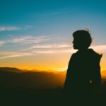 Contemplative Woman outside with a sunset in the background.